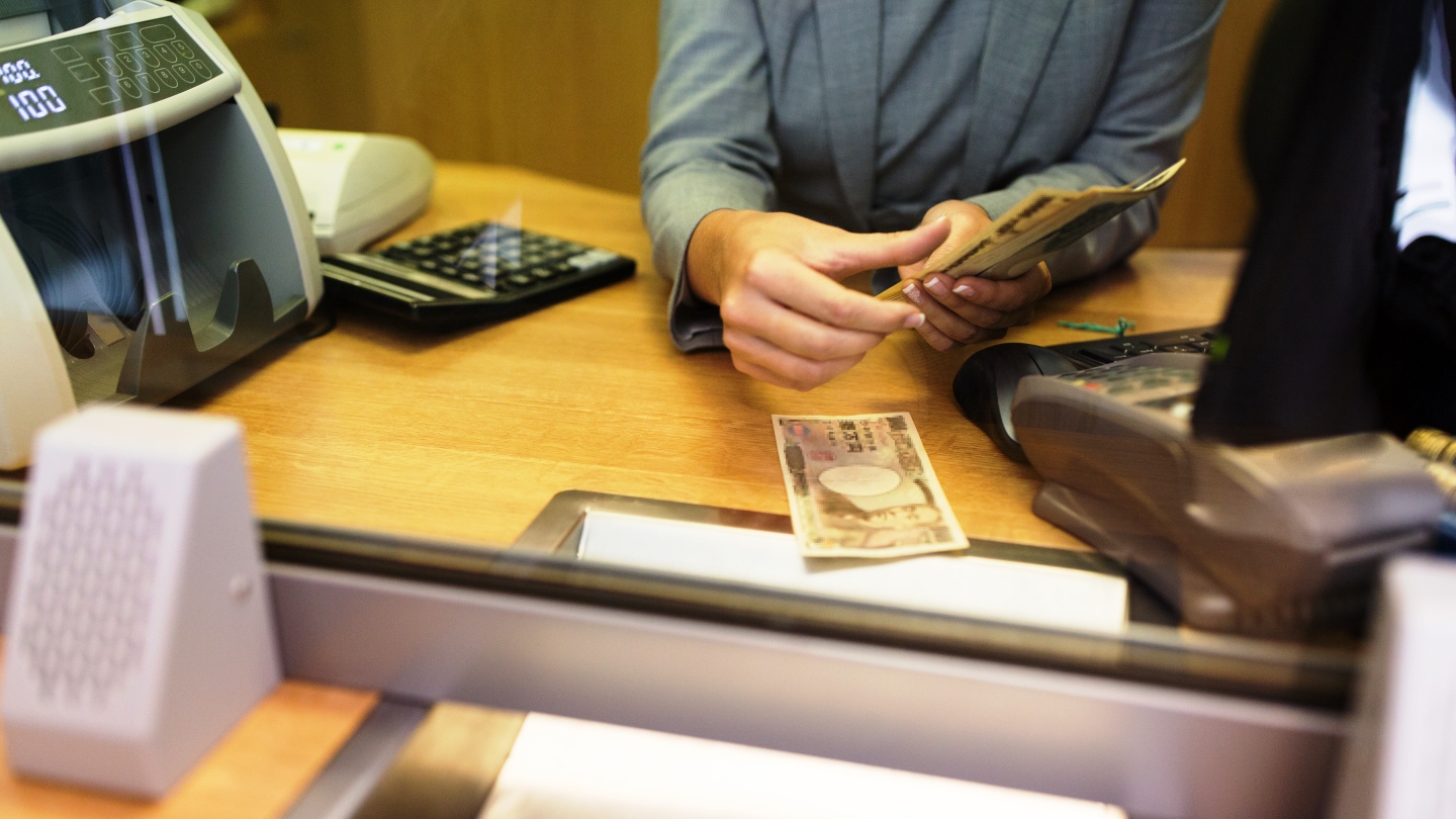 Image of a person counting money on a desk.